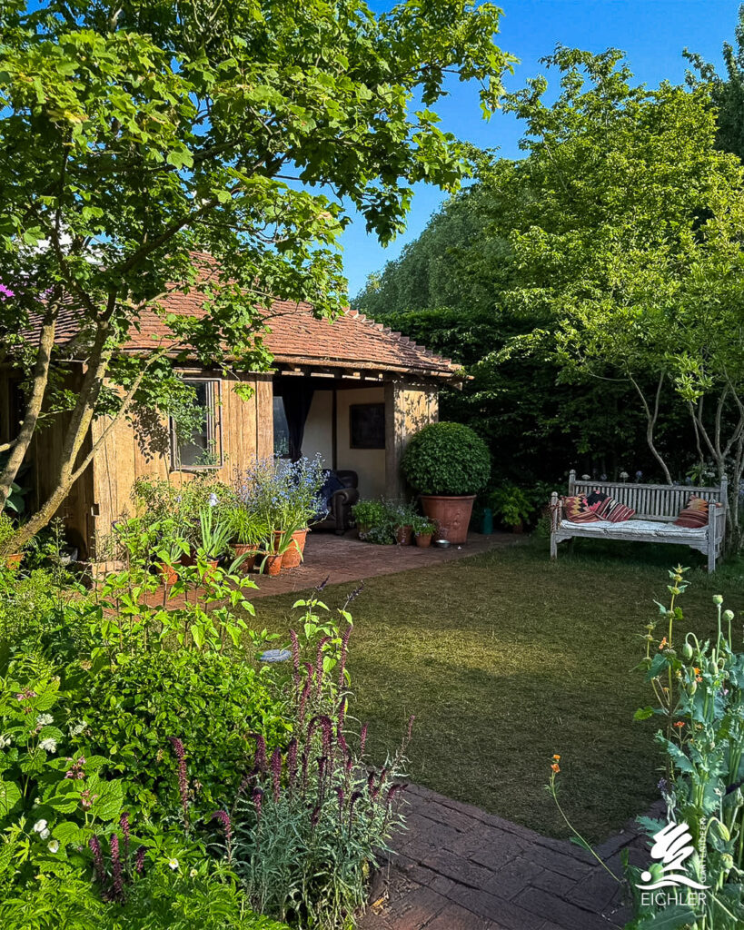 Chelsea Flower Show, Garten mit Gartenhaus, Bank, Wiese und bunten Pflanzen