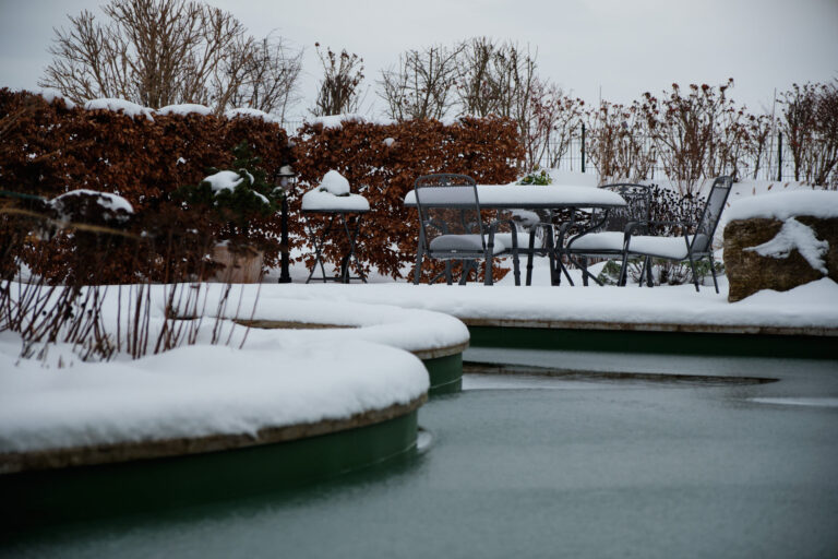 Gefrorener Naturpool mir Sitzecke im Hintergrund