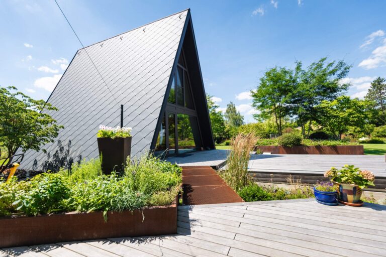 Spitzhaus mit Holzterrasse und hochgelegtem Metallweg