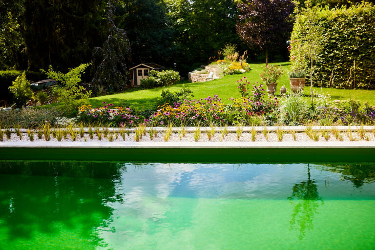 Blick über den Naturpool auf große Rasenfläche