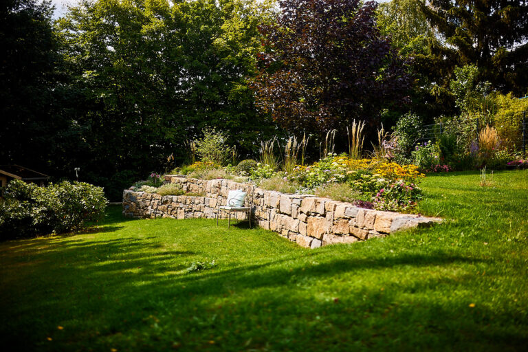 Natursteinmauer mit Sitzgelegenheit davor