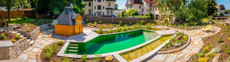 Naturpool mit Natursteintreppen neben Holzsauna