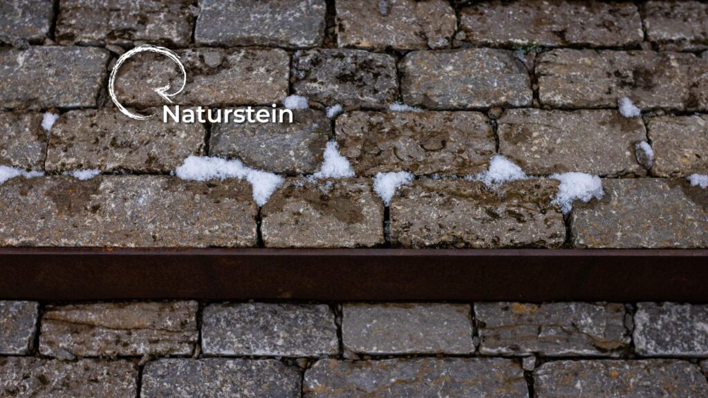 Nahaufnahme Naturstein mit Schnee und Cortenstahl