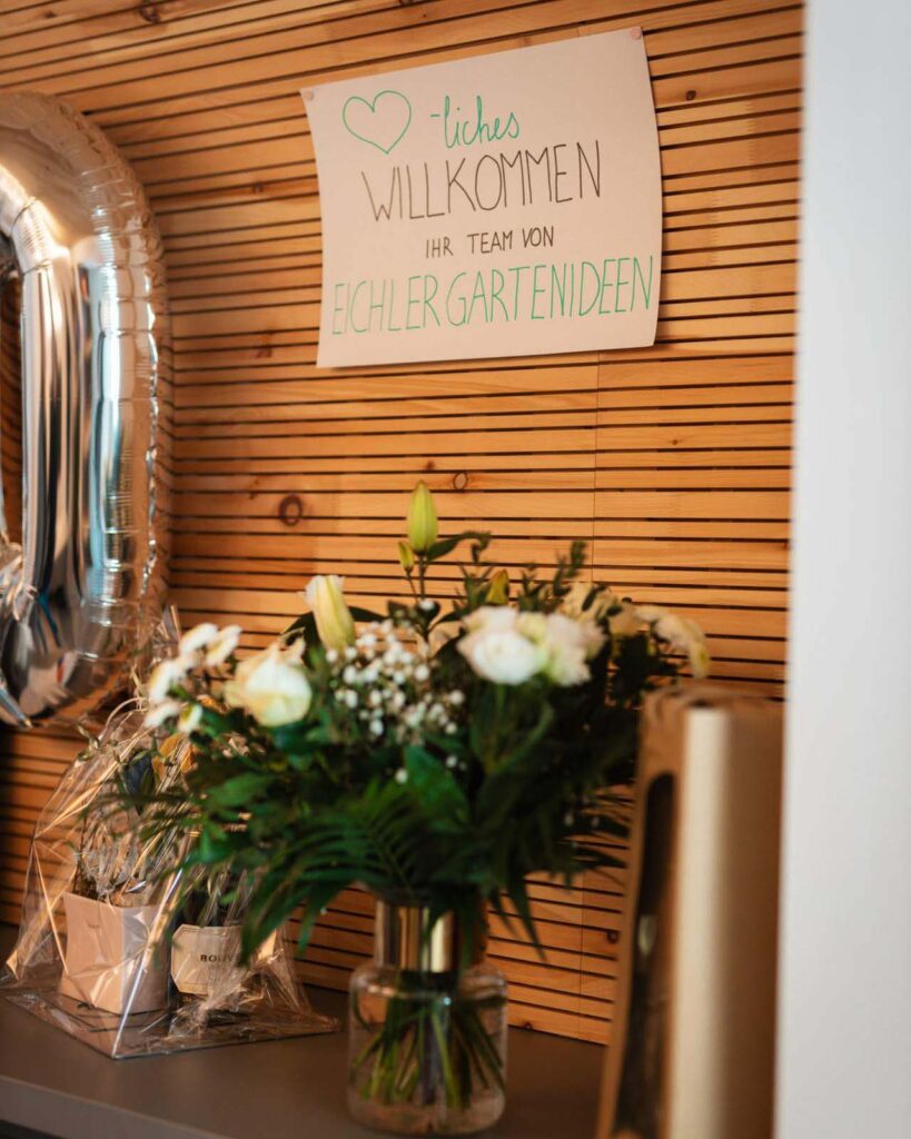 Blumemstrauß mit weißen Rosen und einem Willkommenschild von Eichler Gartenideen