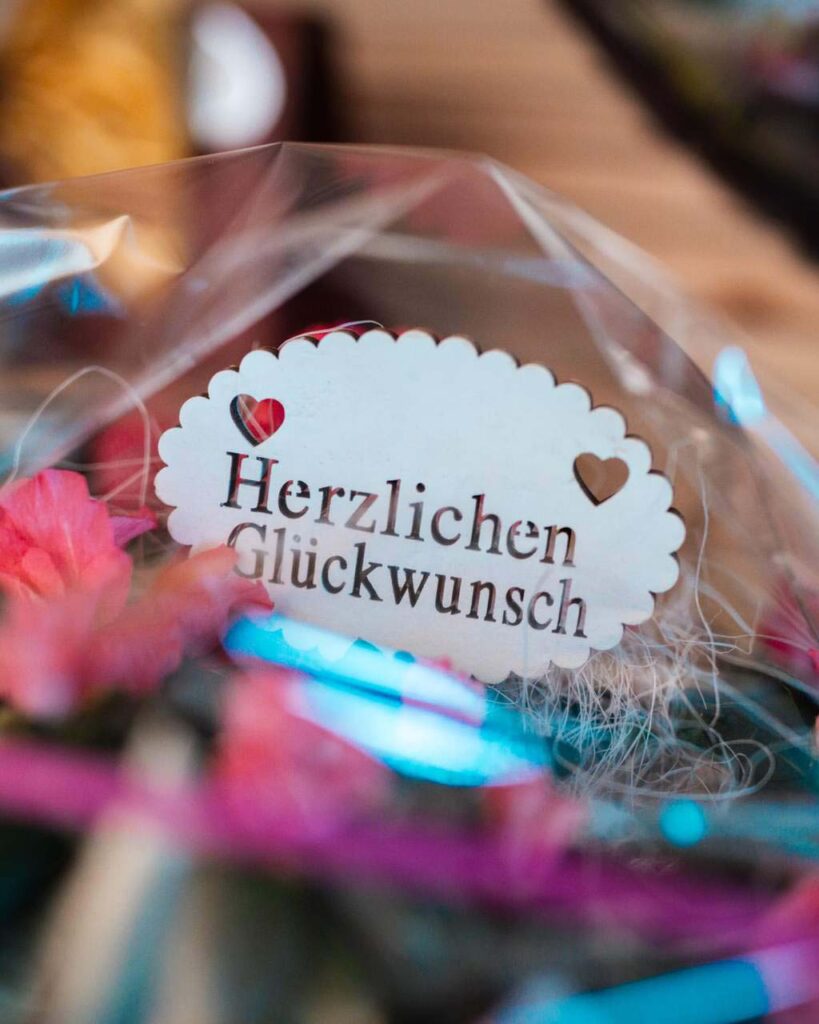 Nahaufnahme einer "Herzlichen Glückwunsch" Karte in einem Blumengesteck