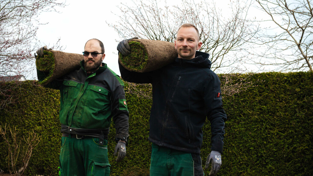 Eichler Mitarbeiter tragen Rollrasen auf der Schulter